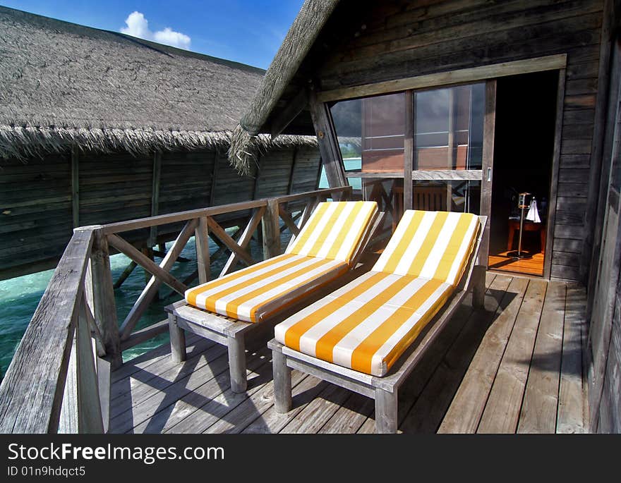 Orange sun bed on a balcony of a resort villa in Maldives. Under blue sky and facing the sea. Orange sun bed on a balcony of a resort villa in Maldives. Under blue sky and facing the sea.