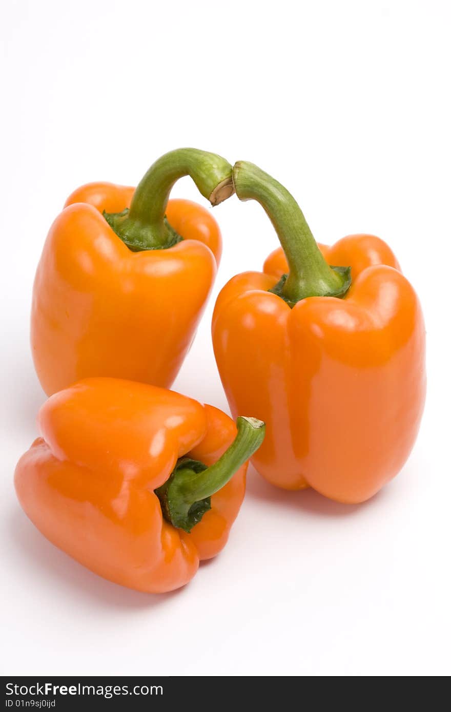 Three orange sweet peppers. Isolated over white background.