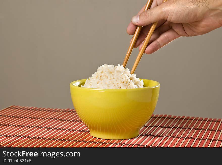 Hand with Chinese chopsticks with a bowl of rice. Hand with Chinese chopsticks with a bowl of rice