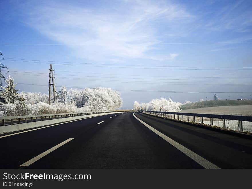 A highway in wintertime with white trees and a white landscape. A highway in wintertime with white trees and a white landscape.