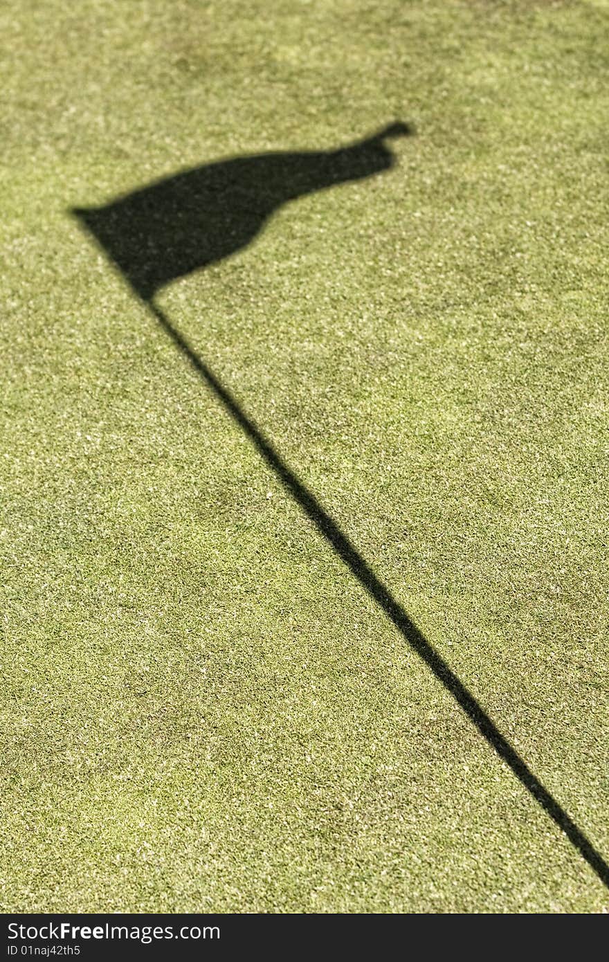 Amazing green golf field showing the hole and the flag shadow, without ball. Amazing green golf field showing the hole and the flag shadow, without ball