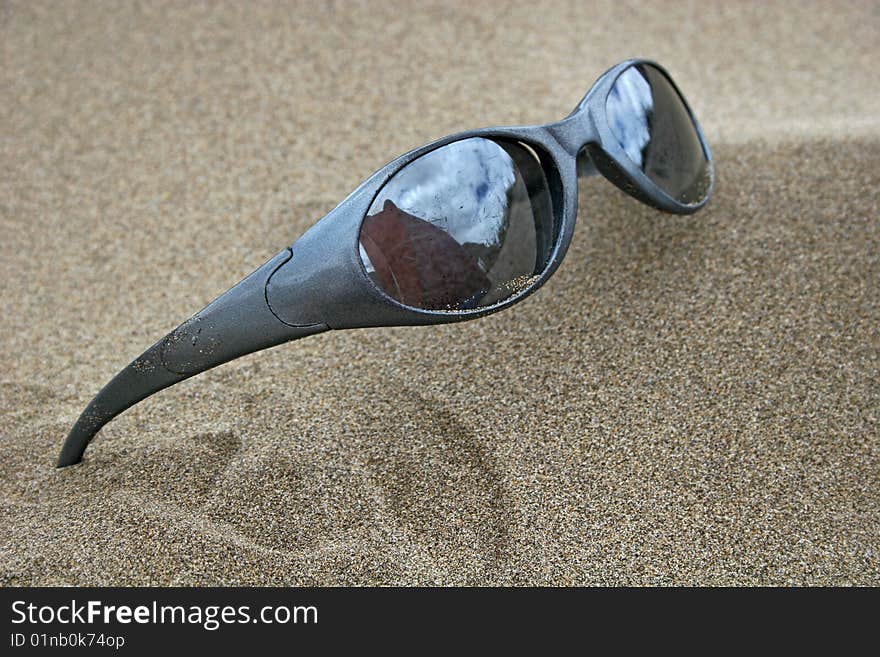 Pair of sunglasses on sandy beach