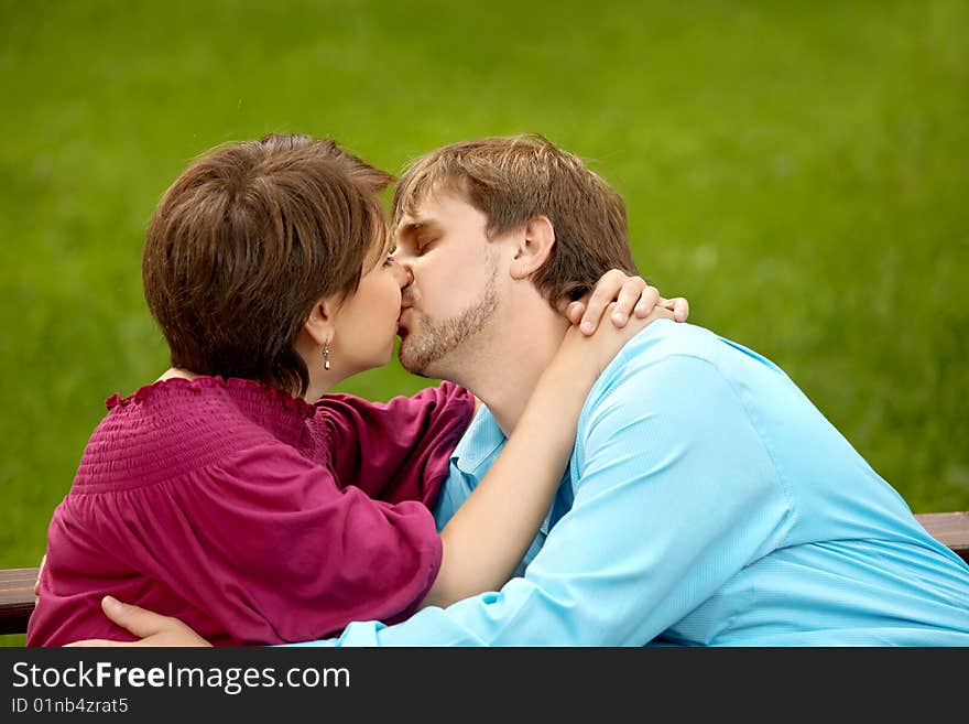 The happy adult couple kisses in park