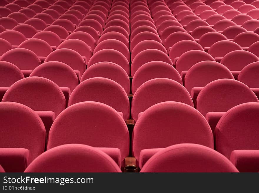 Close-up of empty cinema auditorium with line of pink chairs.