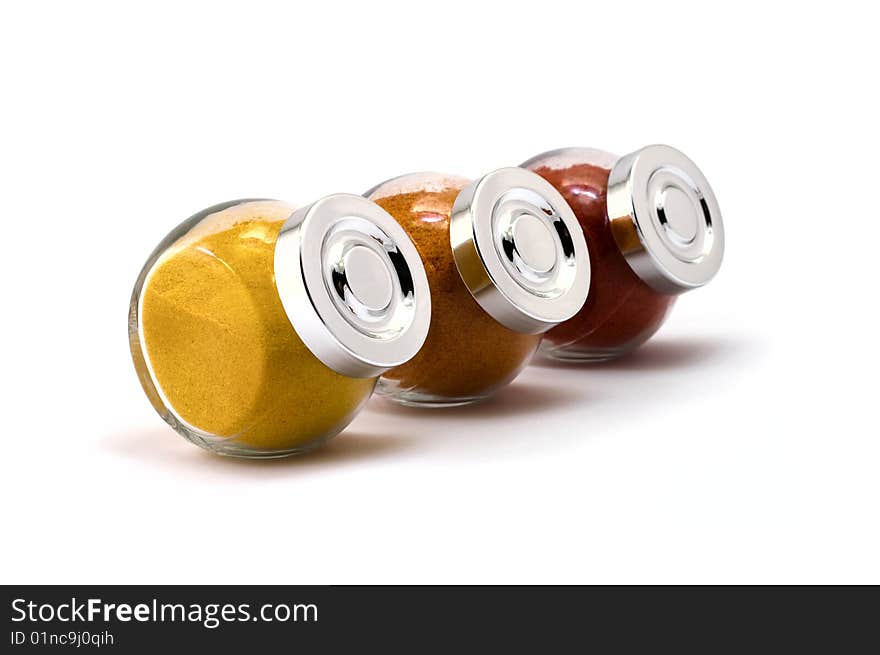 Three jars with filled with spices on isolated white background, focus at 2nd jar cap. Three jars with filled with spices on isolated white background, focus at 2nd jar cap