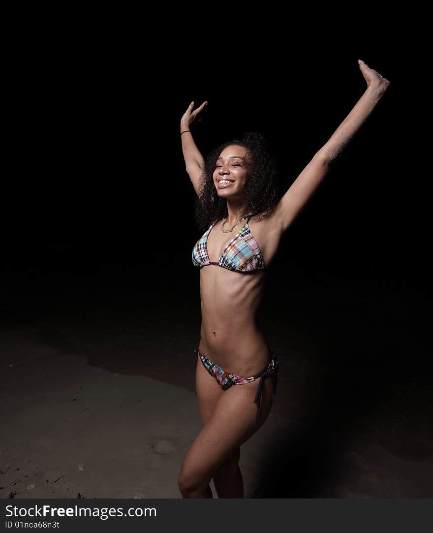 Joyous woman in a bikini extending her arms upward