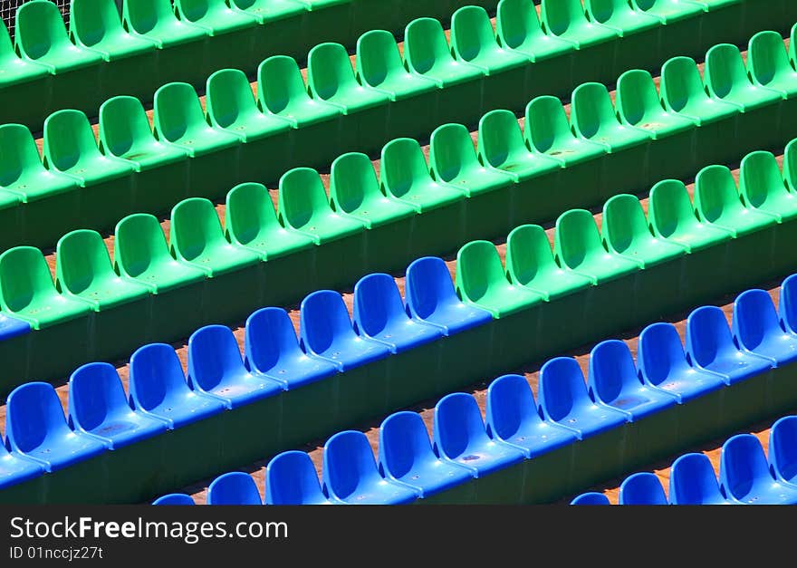 Multi-coloured seats for spectators on tribunes, sunny day