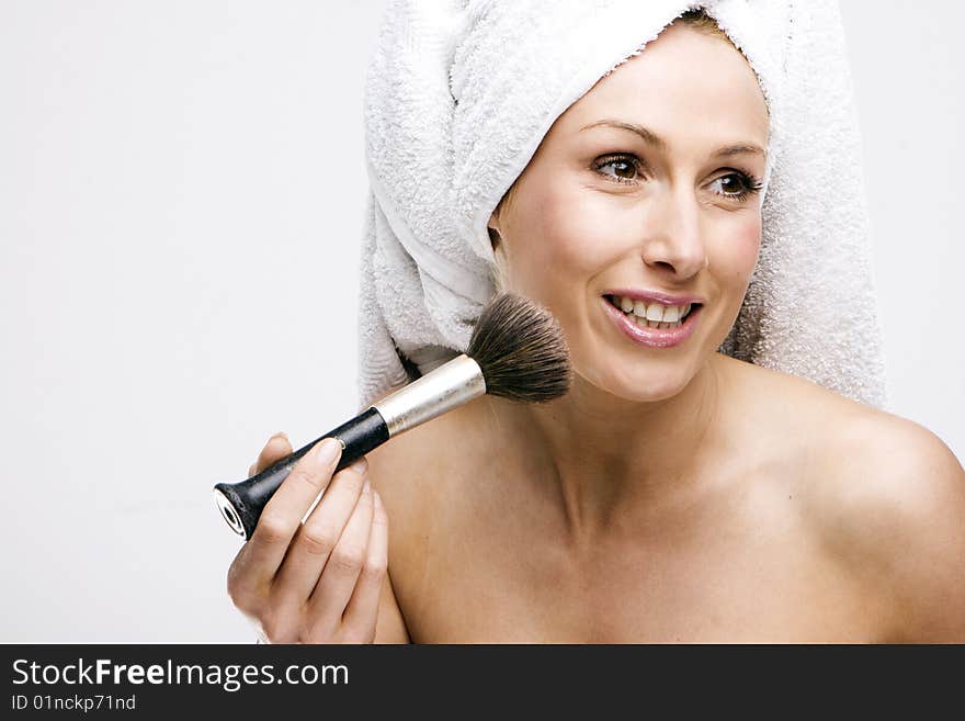 Pretty girl sitting on the bed at home and applying powder with a brush. Pretty girl sitting on the bed at home and applying powder with a brush