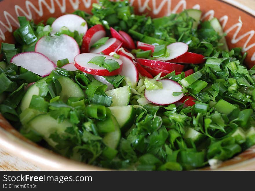 Salad from green goods is poured by  oil in a clay dish. Salad from green goods is poured by  oil in a clay dish