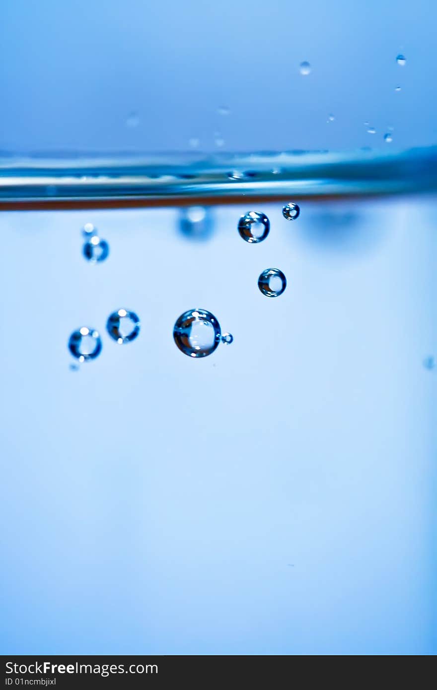 Bubbles in a glass of water on a blue background . Bubbles in a glass of water on a blue background .