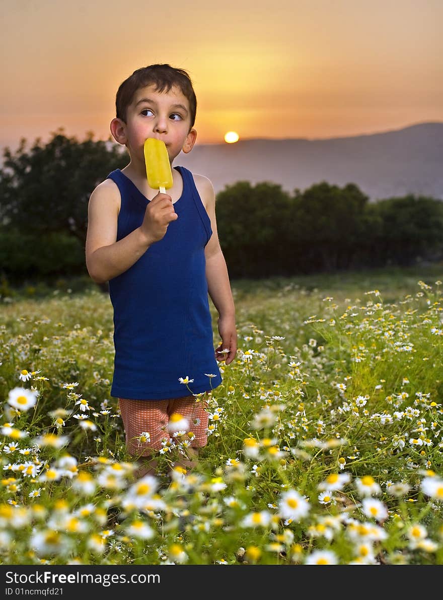 Young boy having an Popsicle out doors at sunset