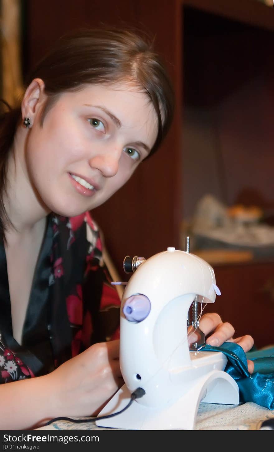 Young woman works at sewing machine in her home. Young woman works at sewing machine in her home