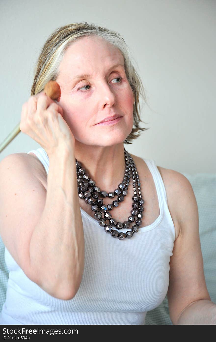 Mature female beauty applying makeup.