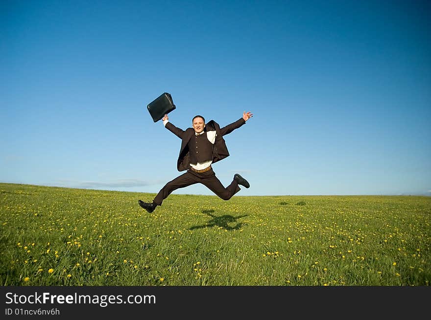 Jumping Businessman in meadow - green grass and blue sky. Jumping Businessman in meadow - green grass and blue sky