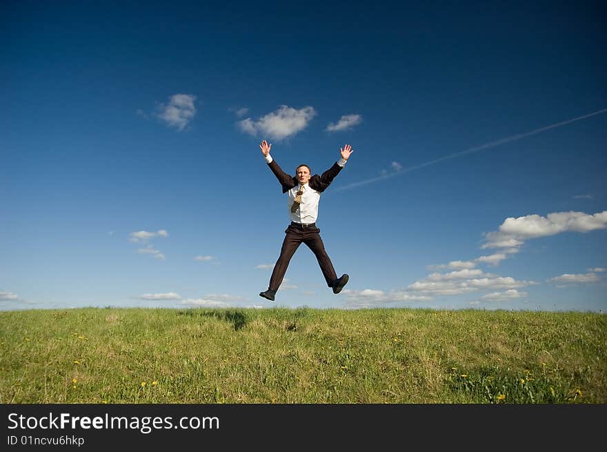 Jumping Businessman in meadow - green grass and blue sky. Jumping Businessman in meadow - green grass and blue sky