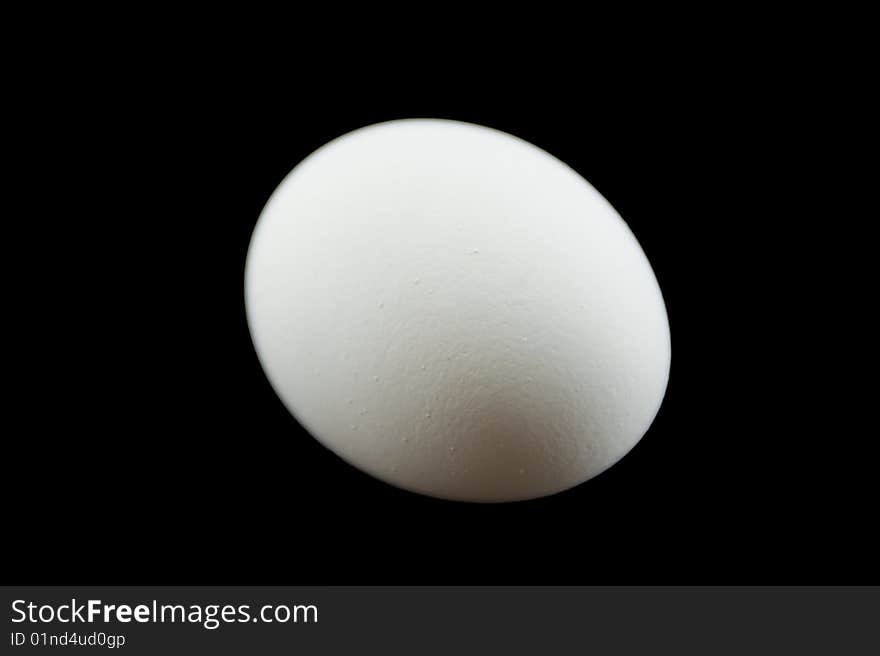 A plain white egg isolated on a black background. A plain white egg isolated on a black background