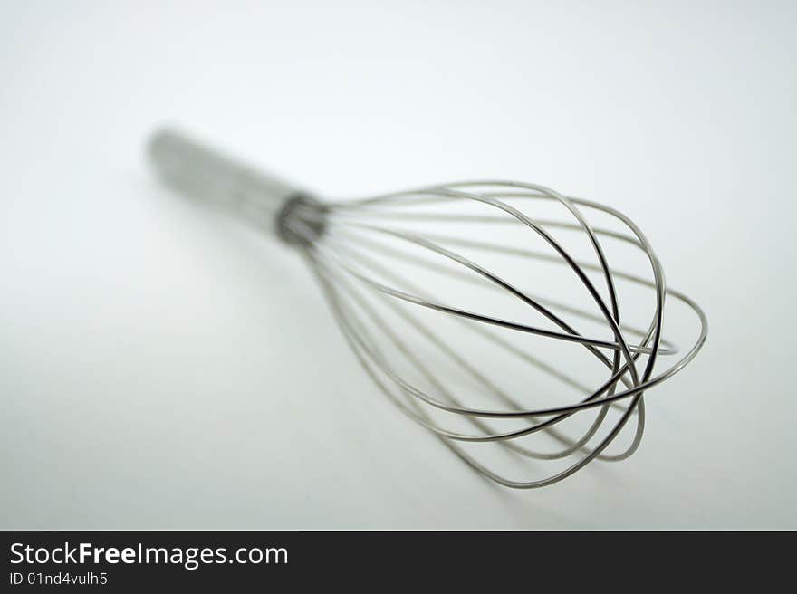 Kitchen stainless steel wisk on its side against a whtie background. Kitchen stainless steel wisk on its side against a whtie background