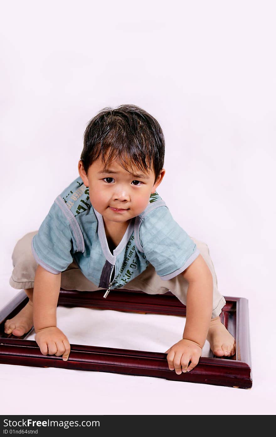 A picture of a little chinese boy squatting on a frame. A picture of a little chinese boy squatting on a frame