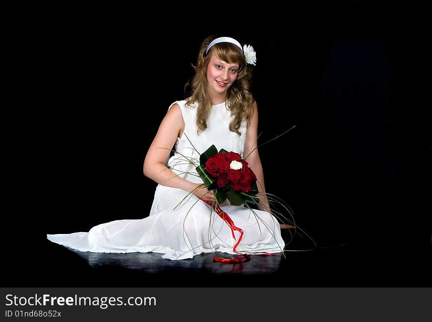 Portrait of a beautiful young bride showing her wedding bouquet of red and white roses on black background, studio shot. Portrait of a beautiful young bride showing her wedding bouquet of red and white roses on black background, studio shot