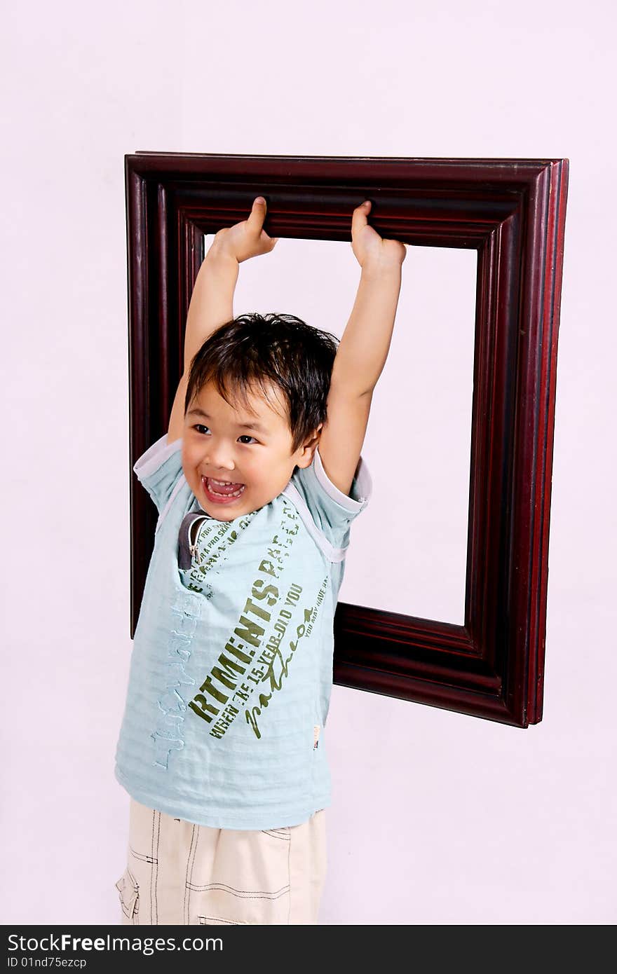 A picture of a little chinese boy holding a frame high up and laughing cheerfully. A picture of a little chinese boy holding a frame high up and laughing cheerfully