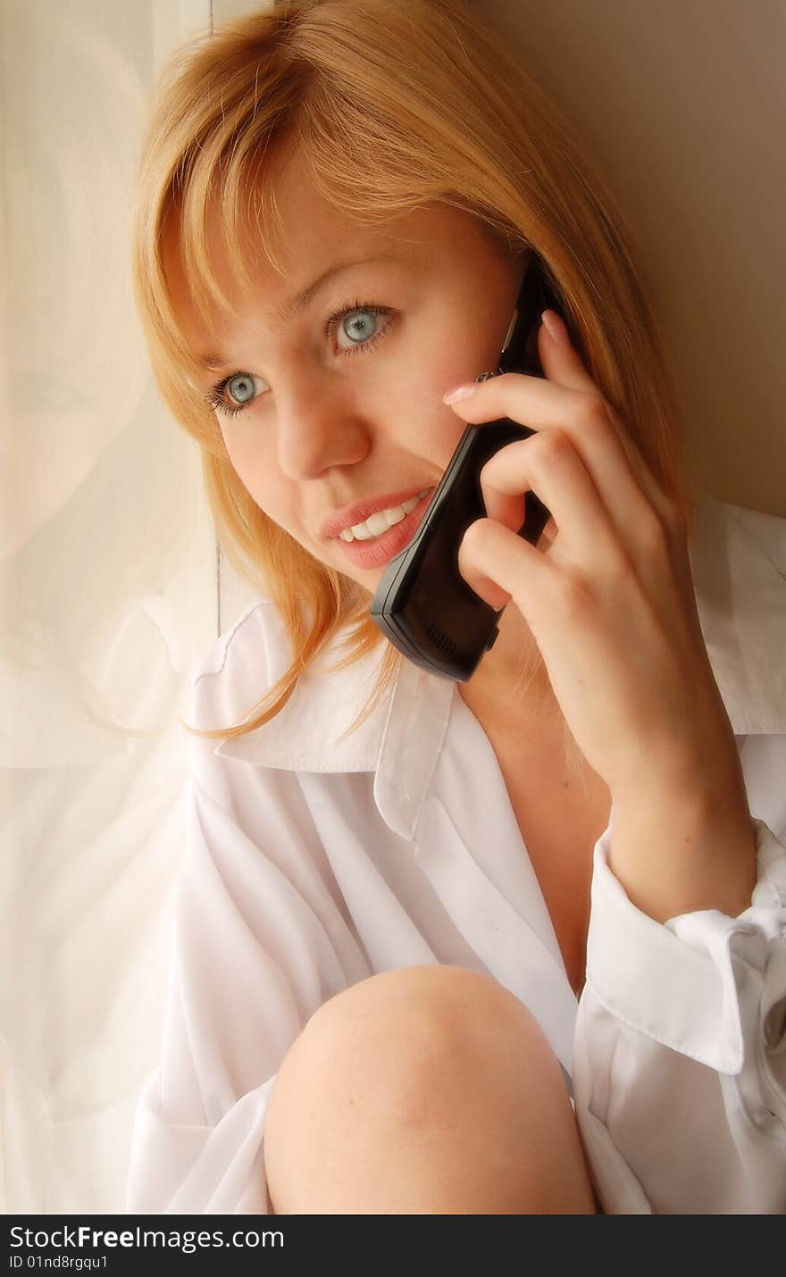 Beautiful young girl with telephon looking in the window. Beautiful young girl with telephon looking in the window