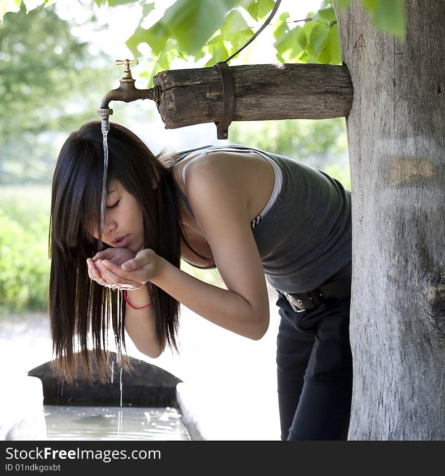 Waters drink of the fountain, teenager is thirsty and refreshes himself