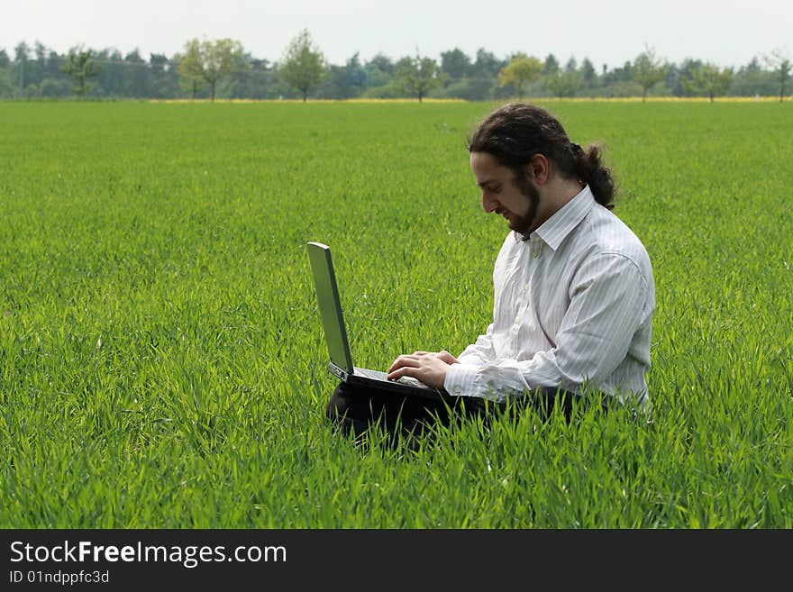 Man sitting on the grass, working