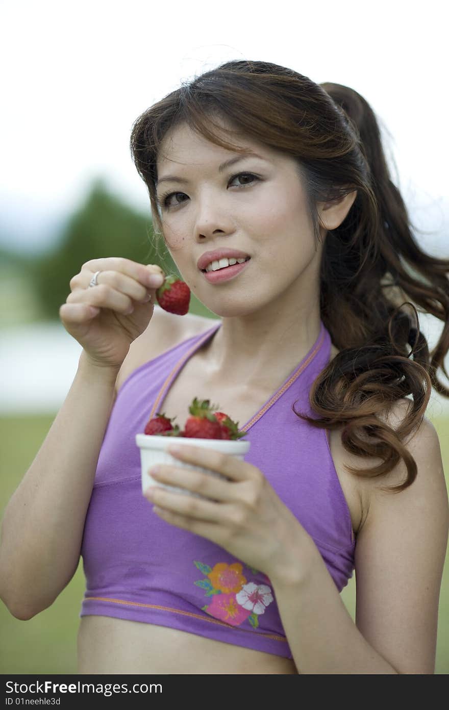 An asian lady taking a break enjoying a bowl of healthy strawberries. An asian lady taking a break enjoying a bowl of healthy strawberries.