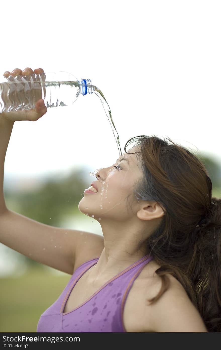 An asian female cooling off by pouring some water on the face. An asian female cooling off by pouring some water on the face.