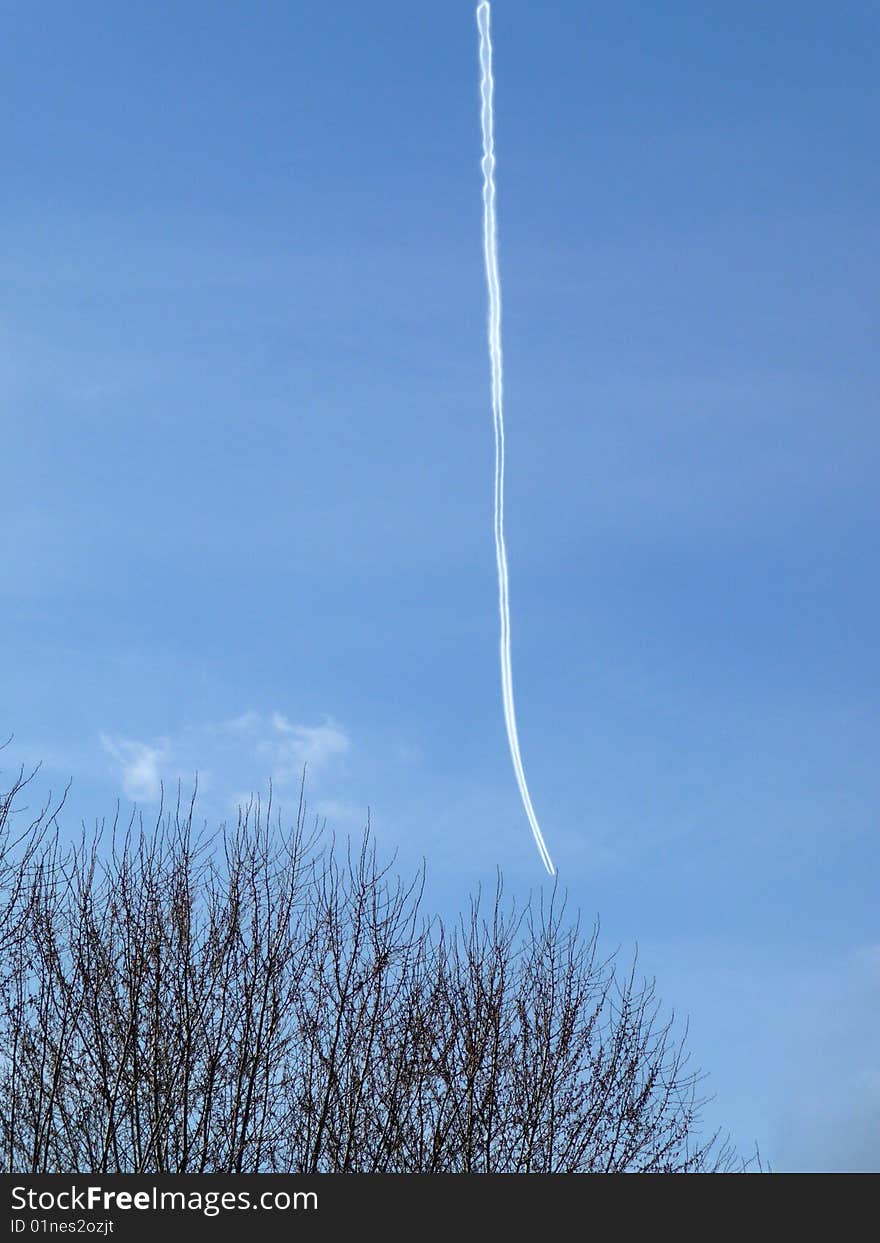 A hard to see airplane and its chemtrail high in the blue sky. A hard to see airplane and its chemtrail high in the blue sky.