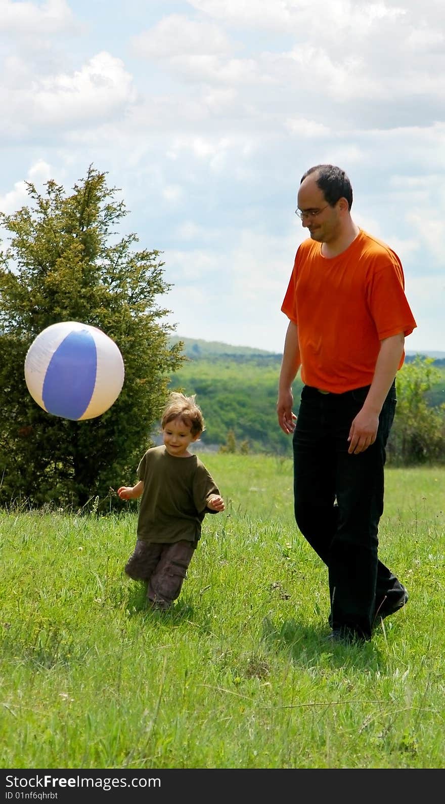 Father and son playing football on nature