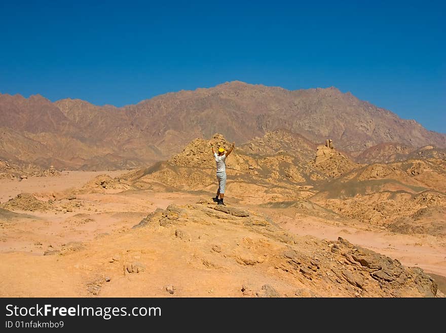 Man with raised hands on the top of hill in desert. Man with raised hands on the top of hill in desert