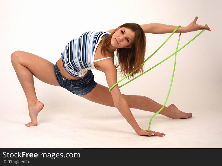 Elegant young flexible woman in blue short jeans with green rope