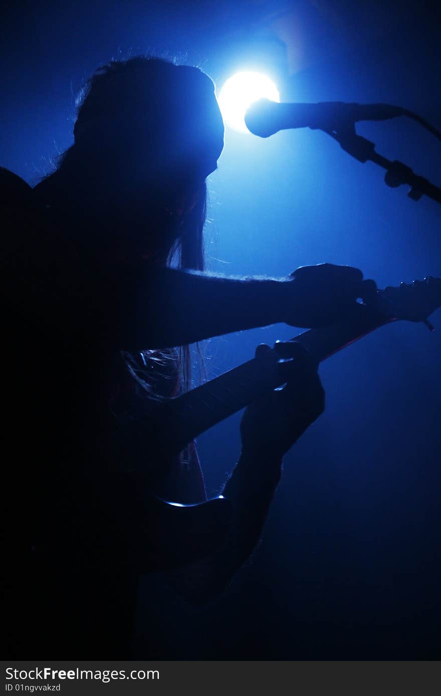 A silhouette of a guitar player in blue lighting. A silhouette of a guitar player in blue lighting