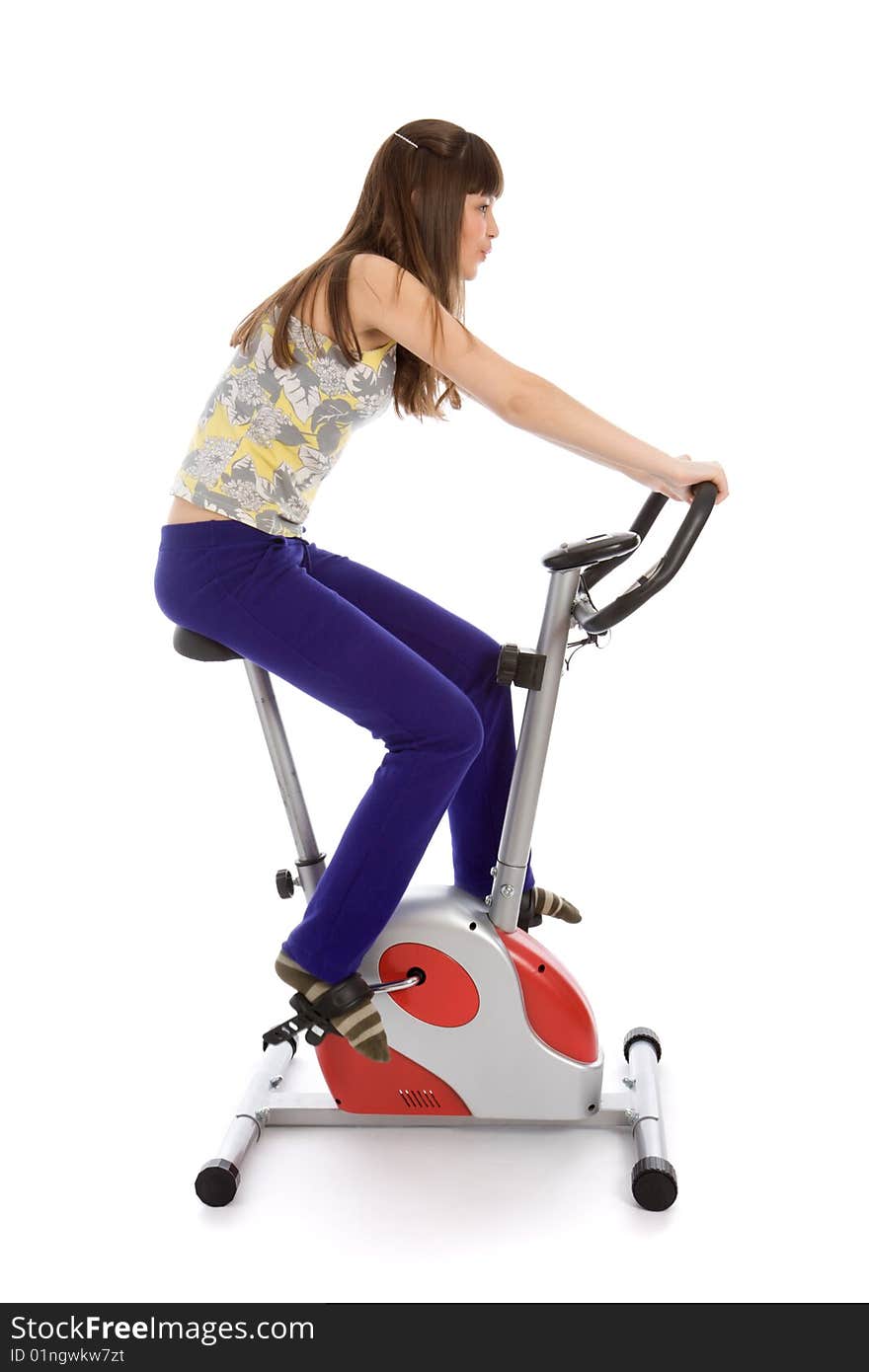 Teenager girl doing fitness on a stationary bike isolated on white. Teenager girl doing fitness on a stationary bike isolated on white