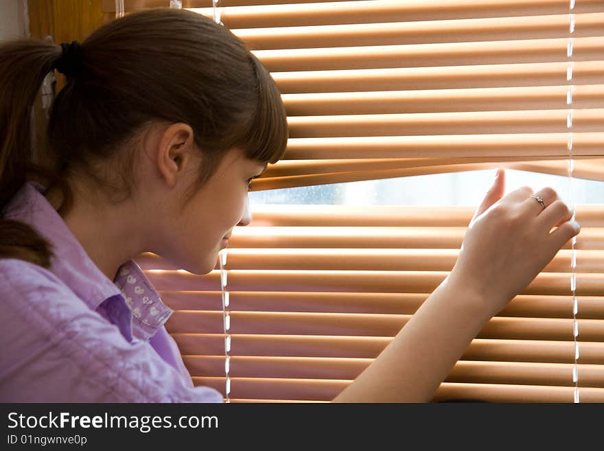 Beautiful teenage girl looks out of the window. Beautiful teenage girl looks out of the window