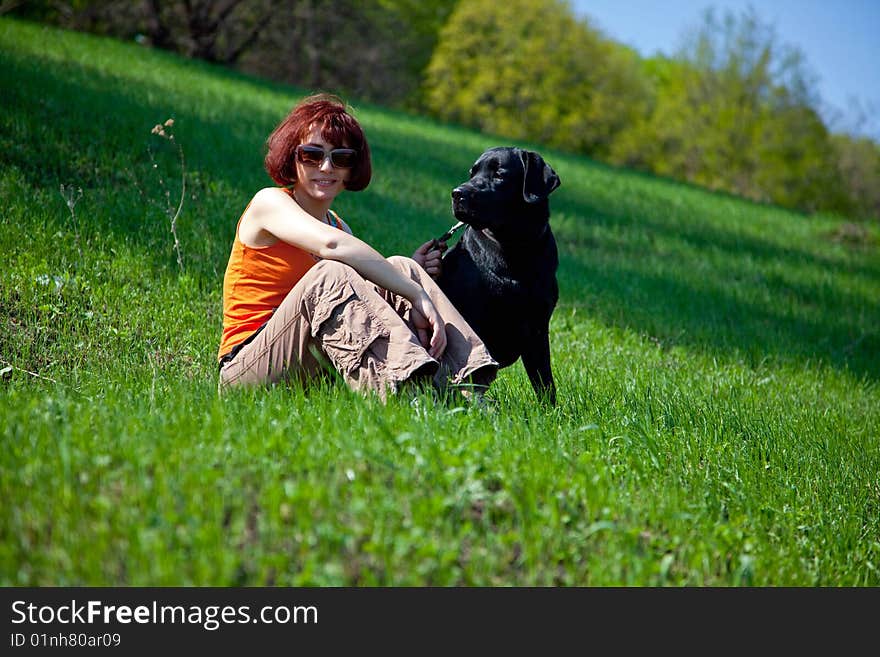 The young woman with black labrador on a green grass. The young woman with black labrador on a green grass