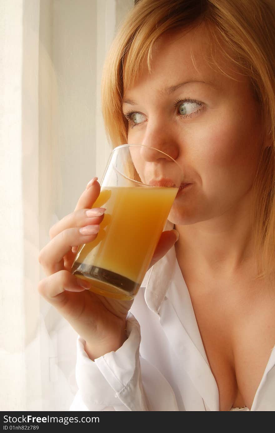 Beautiful girl with glass of juice looking through the window. Beautiful girl with glass of juice looking through the window