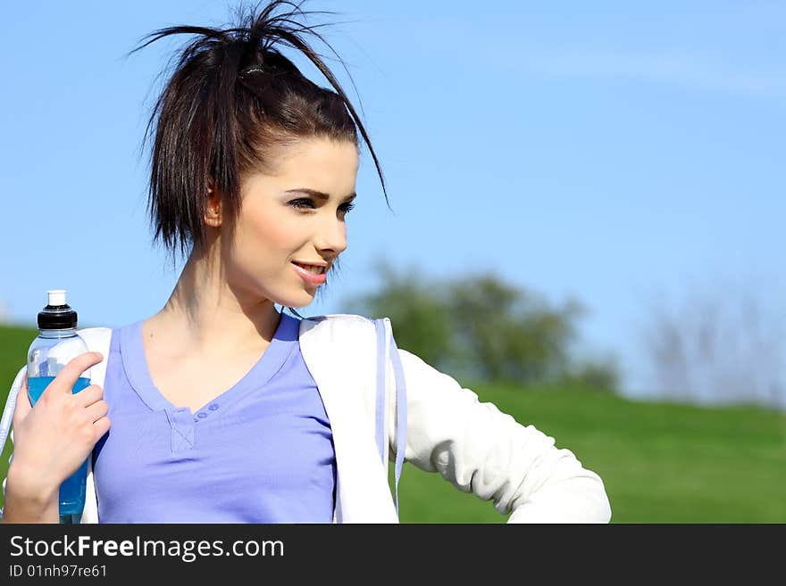 Fitness girl in park drinking water