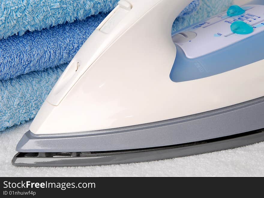 Closeup of an iron next to blue towels. Closeup of an iron next to blue towels