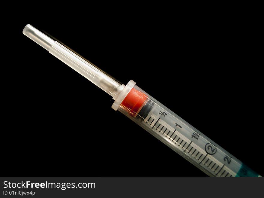 A 3cc syringe with the top on shot on a ultra black background. A 3cc syringe with the top on shot on a ultra black background