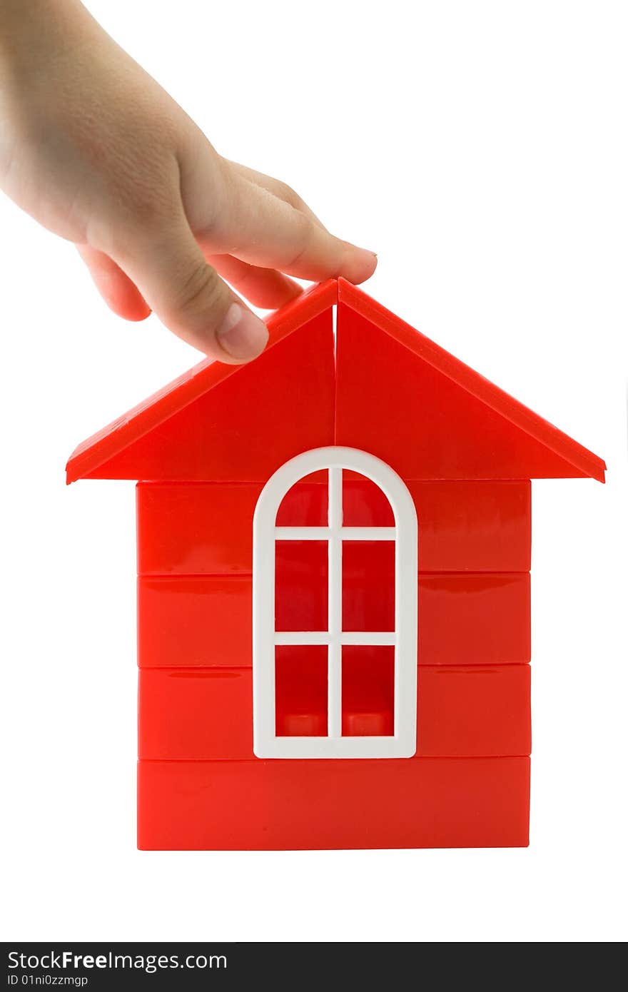 A child's hand holding a  red doll`s house made of details  for designing on a white background. A child's hand holding a  red doll`s house made of details  for designing on a white background