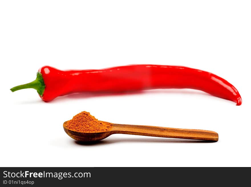 A  pod of red chile pepper and a wooden spoonful of red ground pepper on a white background. A  pod of red chile pepper and a wooden spoonful of red ground pepper on a white background