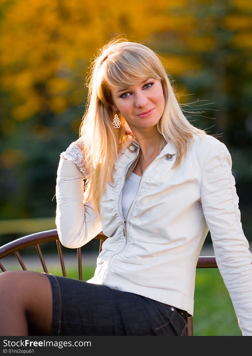 Pretty girl sitting on a bench in autumn park