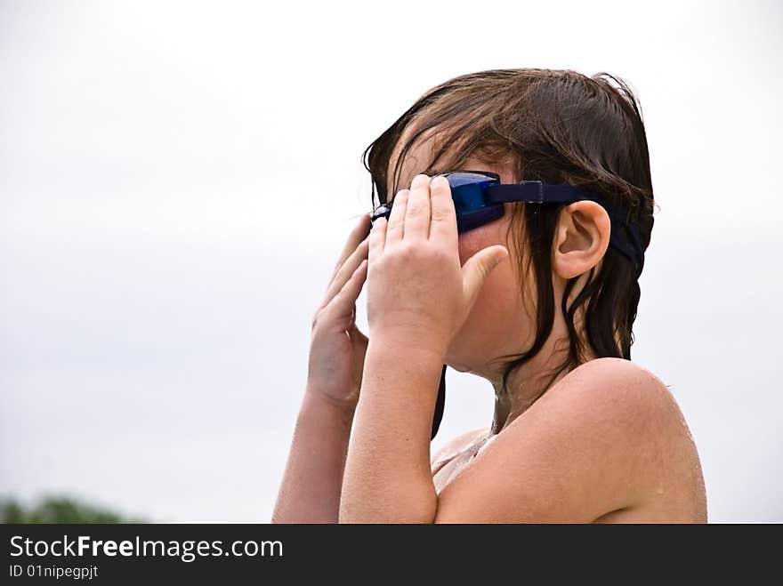 A young girl putting on her goggles getting ready for a swim. A young girl putting on her goggles getting ready for a swim.