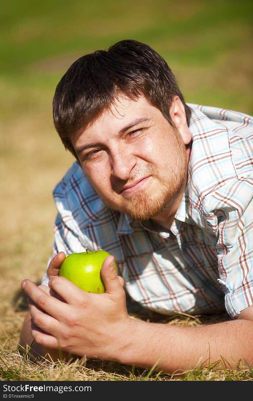 The man with an green apple on the sunlight