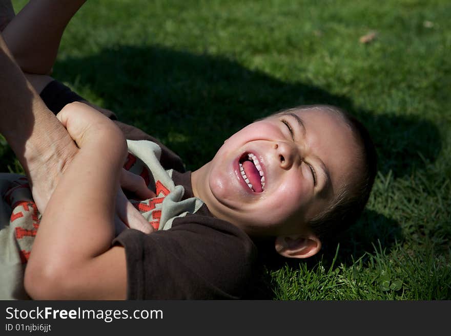 Cute little boy giggling while he is being tickled. Cute little boy giggling while he is being tickled