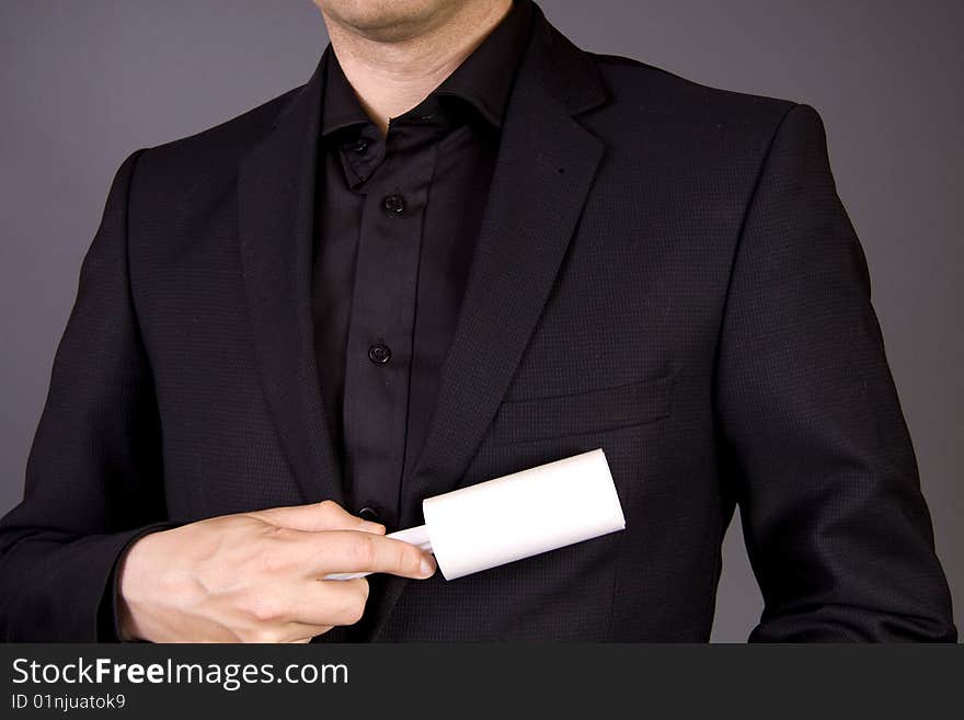 An adult male is cleaning his business suit with a fuzz roller. An adult male is cleaning his business suit with a fuzz roller