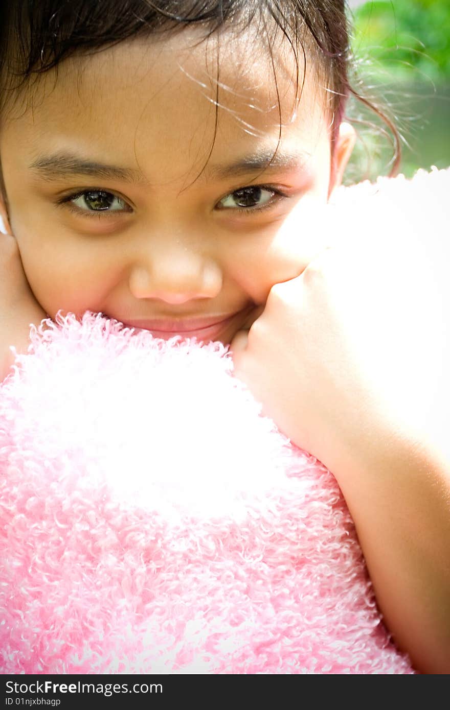 Portrait of sweet asian little girl hugging a pink pillow and smiling at camera. Portrait of sweet asian little girl hugging a pink pillow and smiling at camera