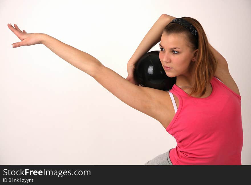 Portrait of young flexible woman in pink t-shirt with black ball. Portrait of young flexible woman in pink t-shirt with black ball